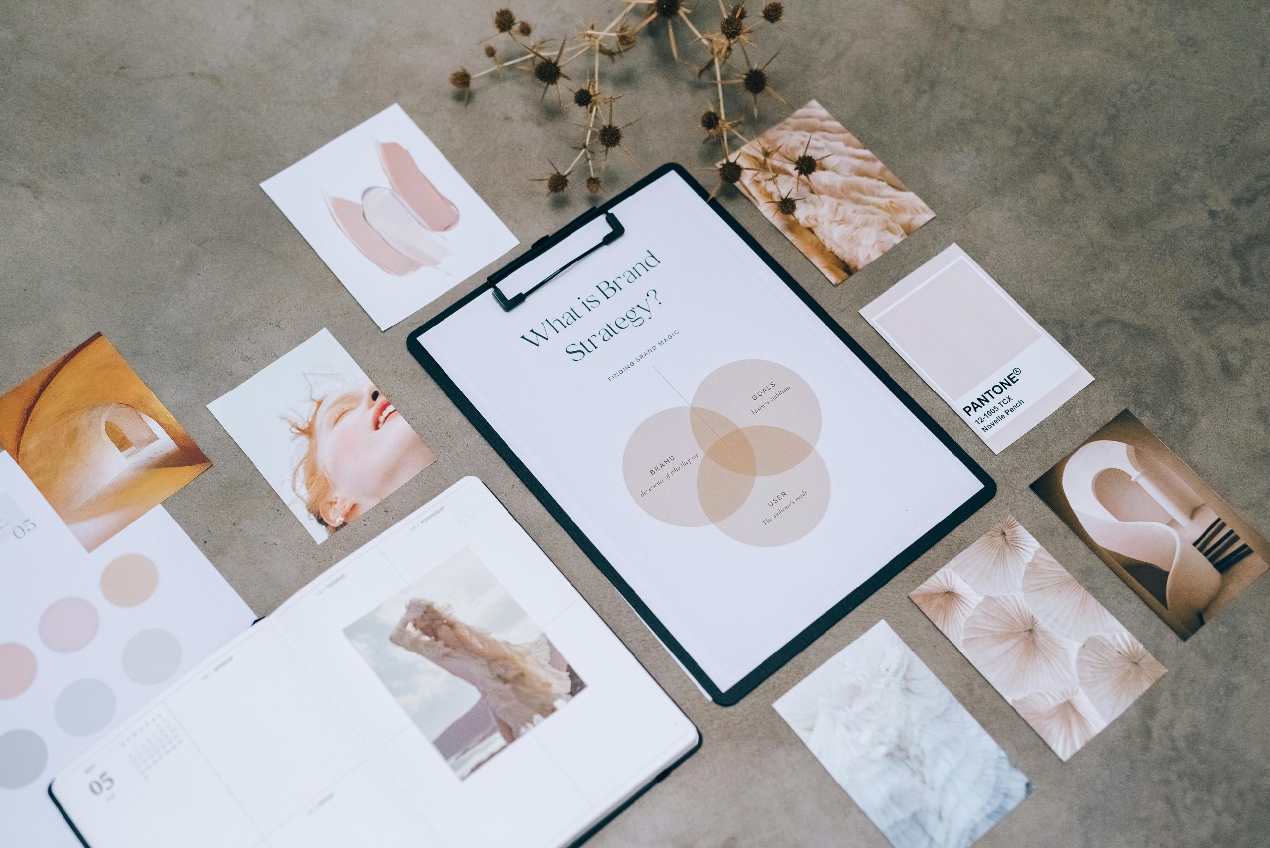 Ein Tisch mit einem Clipboard, das die Überschrift 'What is brand strategy?' zeigt, umgeben von Farbmustern, Designbildern und getrockneten Blumen. Symbol für kreative Dienstleistungen im Bereich Branding und Markenidentität.